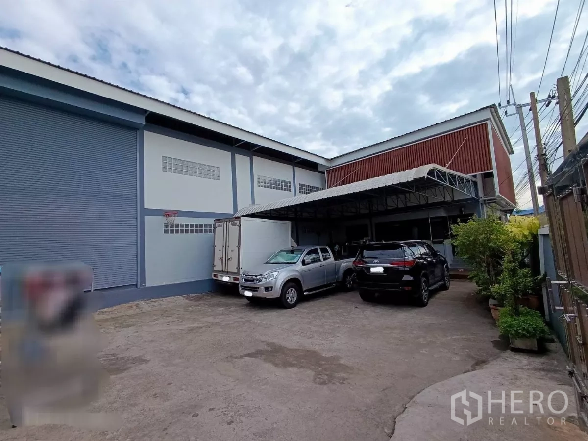 工厂 出租或出售在Bang Khun Thian, Bangkok - 厂区前院与有顶装卸区，停放皮卡，旁有大型卷帘门。