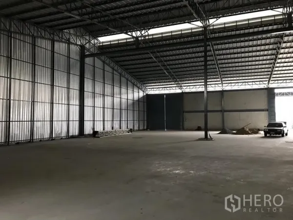 Warehouse for rent in Bang Phli, Samut Prakan - Spacious warehouse interior with high steel truss roof, concrete floor, and large sliding doors.