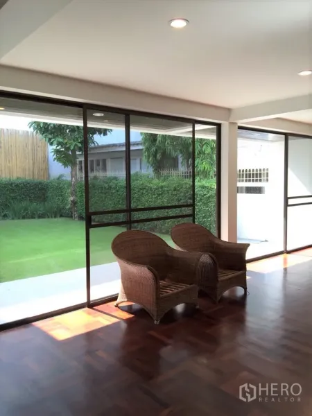 Detached House for rent in Sathon, Bangkok - Bright living room with floor-to-ceiling sliding glass doors opening to a green lawn and garden.