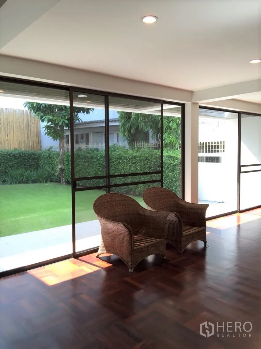 Detached House for rent in Sathon, Bangkok - Bright living room with floor-to-ceiling sliding glass doors opening to a green lawn and garden.