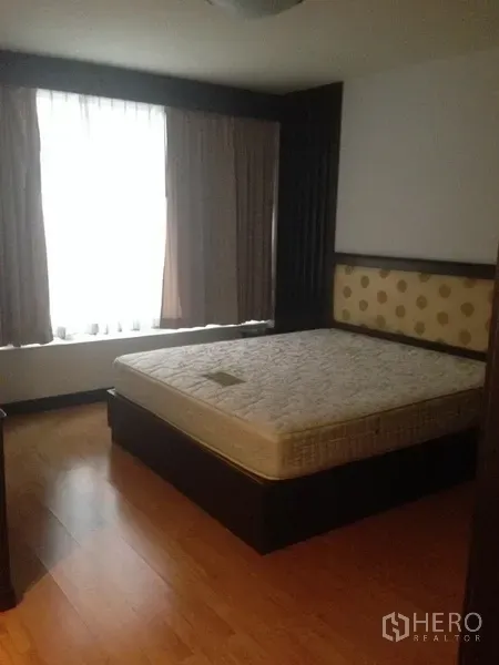 Condominium for rent in Pathum Wan, Bangkok - Primary bedroom with large window, wood flooring and upholstered headboard.