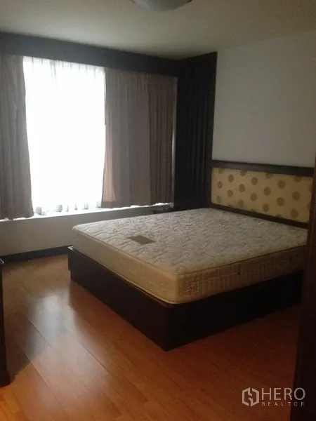 Condominium for rent in Pathum Wan, Bangkok - Primary bedroom with large window, wood flooring and upholstered headboard.