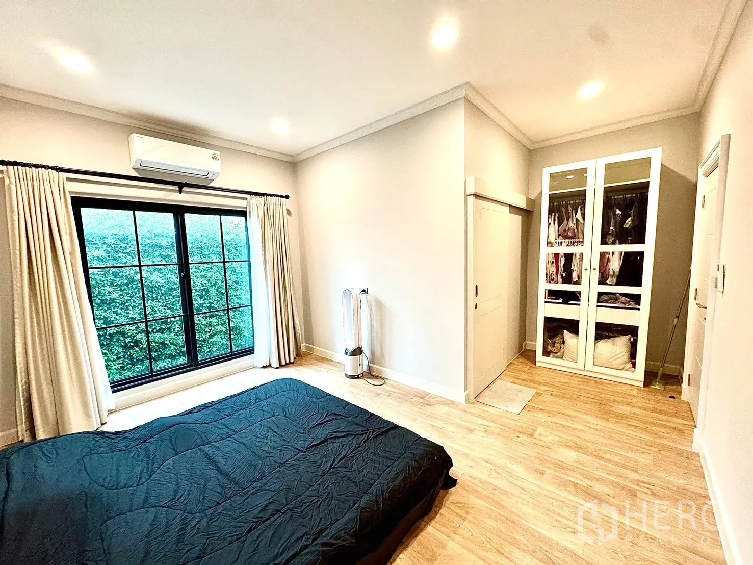 Detached House for rent in Bang Phli, Samut Prakan - Bright bedroom with wood flooring, large black-framed window, light curtains, air conditioner and built-in wardrobe.