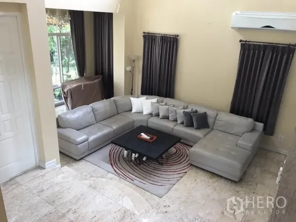 独立式住宅 出租 - 舒适起居角，灰色转角沙发、地毯、分体空调与高窗配深色窗帘。