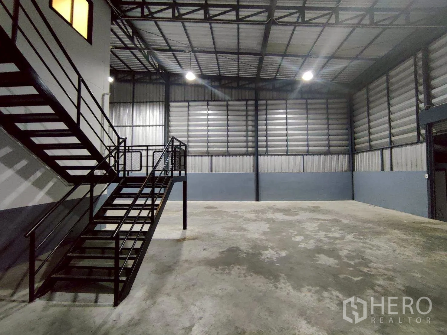 โกดัง for rent in Lam Luk Ka, Pathum Thani - ภาพใกล้ของบันไดเหล็กข้างพื้นที่เก็บสินค้าความสูงมากและผนังระบายอากาศ.