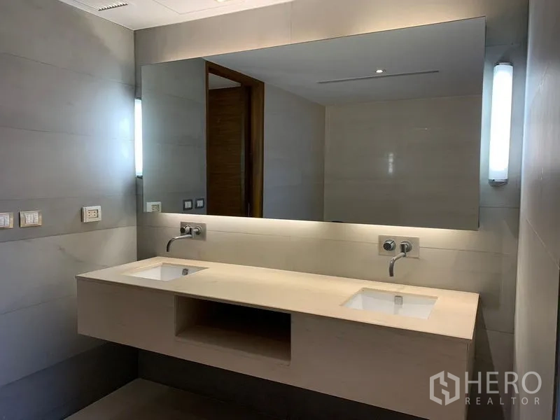 Condominium for rent - Modern bathroom with twin basins and backlit mirror.