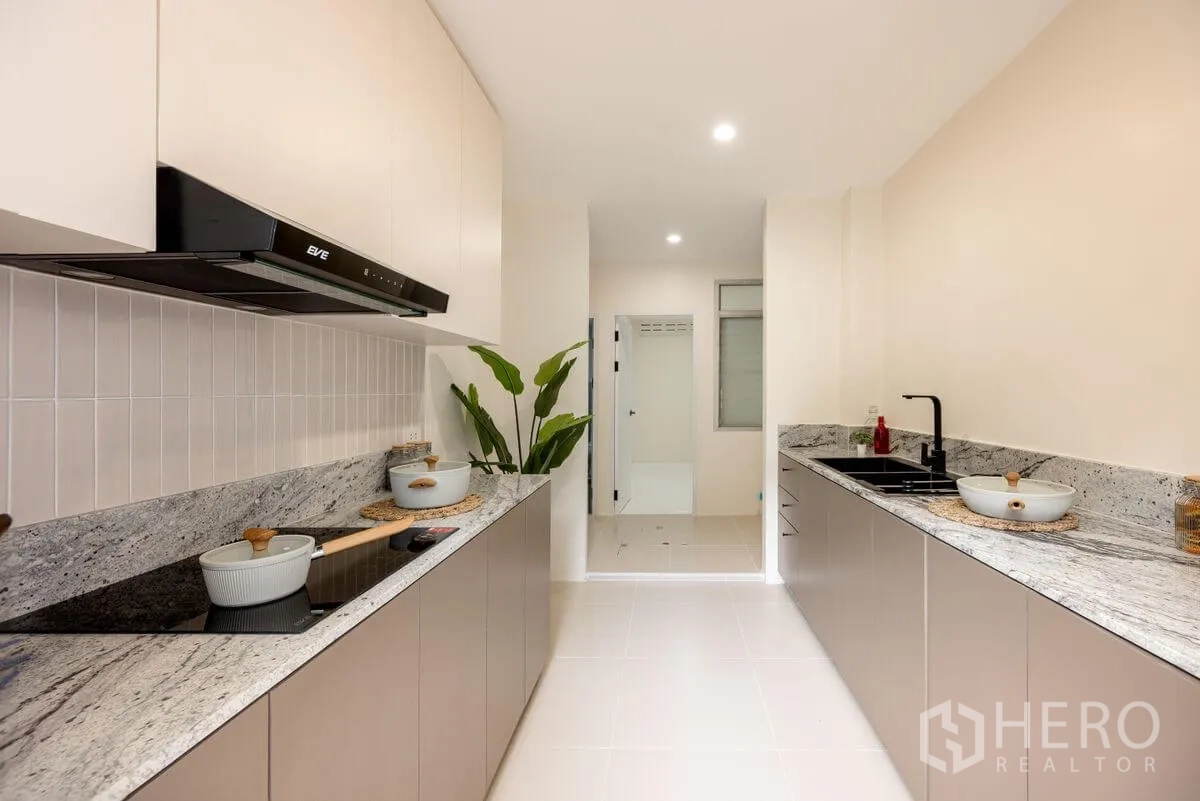 Detached House for rent or sale in Chatuchak, Bangkok - Galley kitchen with twin counters, granite worktops, induction hob, and sink.