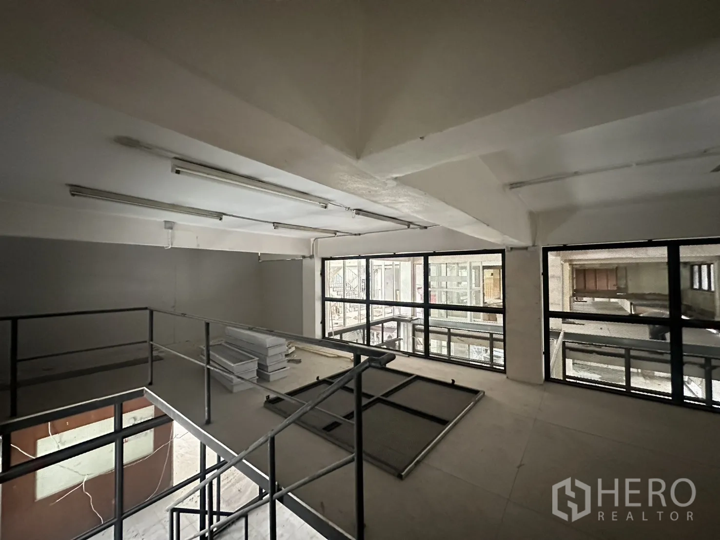 零售空间 for rent in Watthana, Bangkok - 夹层空间设金属栏杆与日光灯，整面框架窗可眺望内侧中庭。