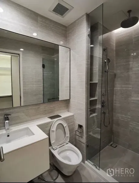 公寓 出租在Bang Rak, Bangkok - 现代卫浴配大镜面洗手台与玻璃隔断顶喷花洒。