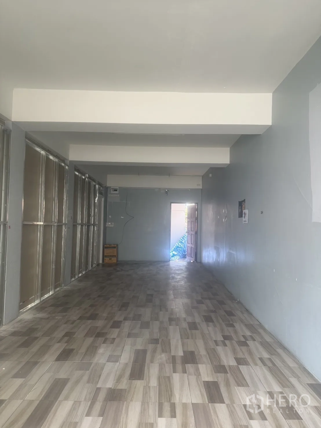 Retail Space for rent in Pathum Wan, Bangkok - Open-plan retail interior with wood-look tile flooring, light gray walls, and a rear doorway.