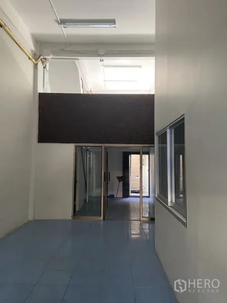 店屋 出租在Bang Na, Bangkok - 一层挑高大厅，蓝色地砖与玻璃推拉隔断通向后方