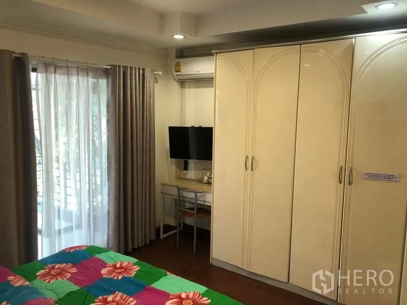 พื้นที่ขายปลีก ให้เช่าในKhlong Toei, Bangkok - ห้องนอนมีตู้เสื้อผ้า ทีวี โต๊ะทำงาน และประตูกระจกเปิดสู่ระเบียง