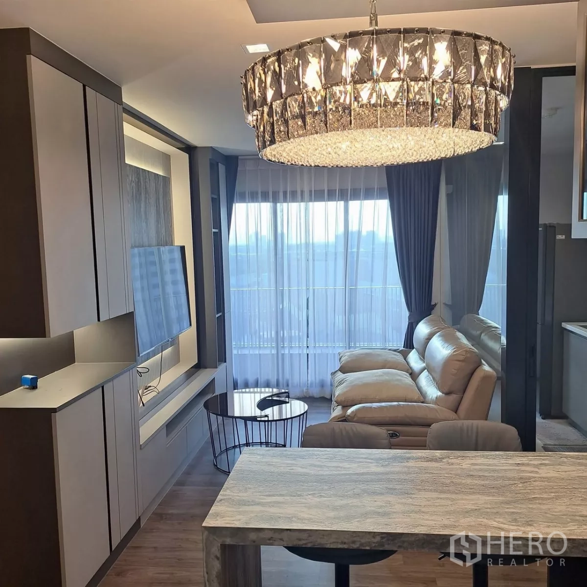 คอนโด ให้เช่าในChatuchak, Bangkok - ห้องนั่งเล่นสไตล์โมเดิร์นพร้อมโคมระย้า โซฟาหนัง ผนังทีวีบิลท์อิน และหน้าต่างแบบฟูลเฮย์ท