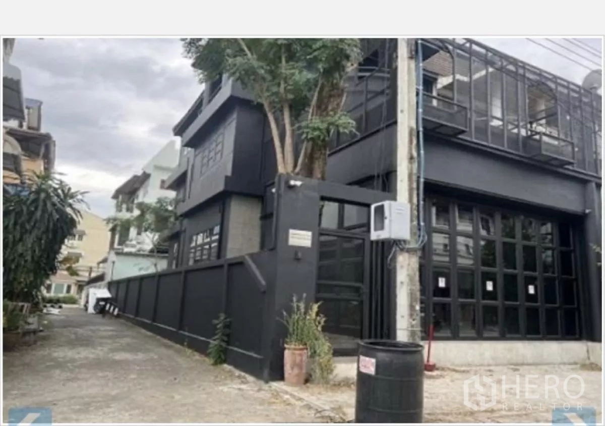 Home Office for rent in Wang Thonglang, Bangkok - Corner exterior of a black modern townhouse with gated entry and glass facade.