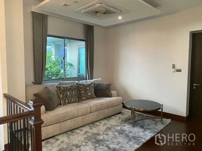 บ้าน ให้เช่าหรือขายในLat Krabang, Bangkok - ห้องนั่งเล่นชั้นบนแบบอบอุ่น มีโซฟา โต๊ะกลม และหน้าต่างรับวิวบนพรมฟู