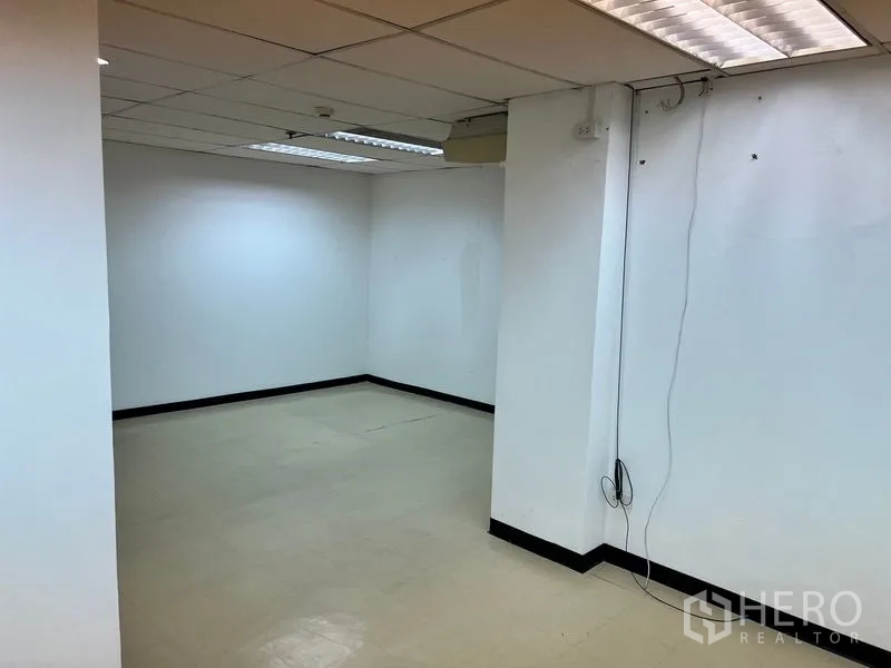 办公空间 出租在Pathum Wan, Bangkok - 办公角落，瓷砖地面、吊顶照明，墙面设有电源与网络端口。