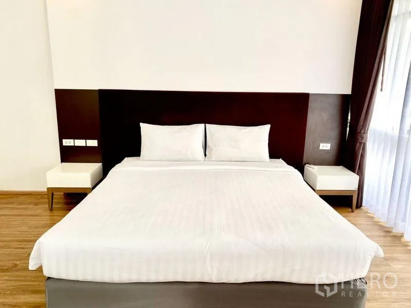 คอนโด ให้เช่าในKhlong Toei, Bangkok - ห้องนอนเตียงใหญ่ หัวเตียงสีน้ำตาล โต๊ะข้างสองข้าง และหน้าต่างใกล้ระเบียง