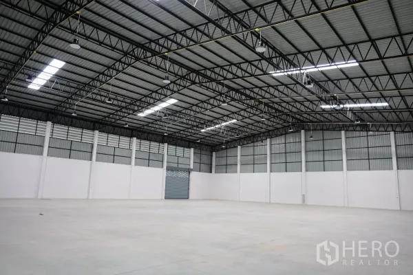 Factory for rent or sale in Bang Len, Nakhon Pathom - Clear-span warehouse interior with a 9‑meter high steel truss roof, LED lighting and smooth concrete floor.