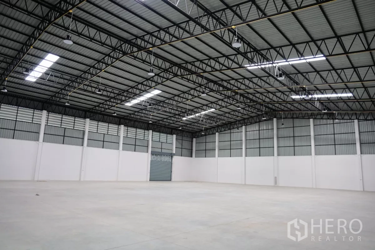 Factory for rent or sale in Bang Len, Nakhon Pathom - Clear-span warehouse interior with a 9‑meter high steel truss roof, LED lighting and smooth concrete floor.