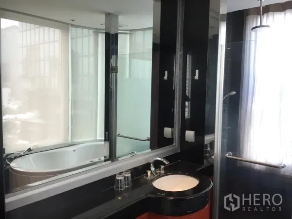 Condominium for rent or sale in Bang Rak, Bangkok - En-suite bathroom with rain shower, vanity, and soaking tub by a large window.