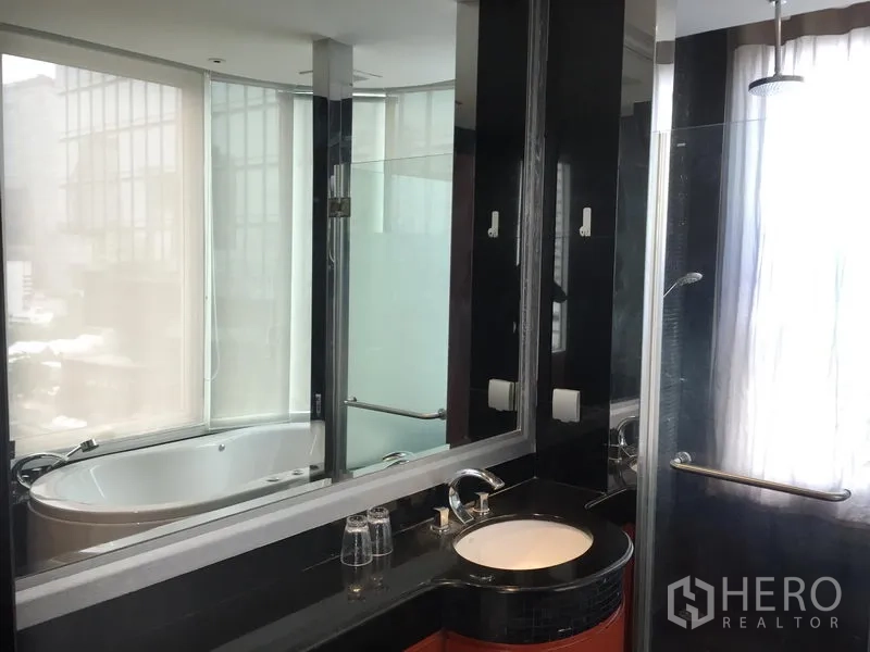 Condominium for rent or sale in Bang Rak, Bangkok - En-suite bathroom with rain shower, vanity, and soaking tub by a large window.