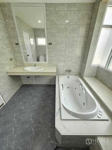 Detached House for sale in Pak Kret, Nonthaburi - Tiled bathroom featuring a built-in bathtub, long vanity and window.