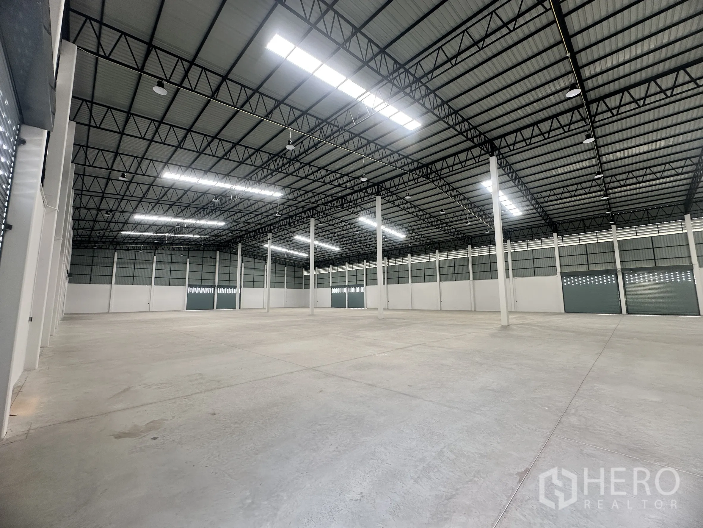 Factory for rent or sale in Bang Len, Nakhon Pathom - Huge warehouse interior with high steel truss ceiling, bright lighting, and smooth concrete floor.