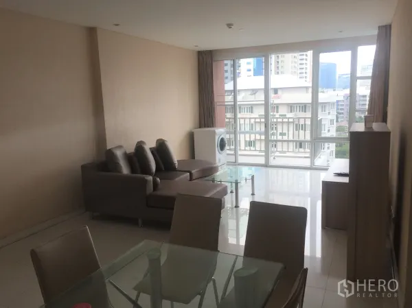 Condominium for rent or sale in Watthana, Bangkok - Bright living room with floor-to-ceiling windows, city outlook, and an in‑unit washer in a Watthana Bangkok condominium.