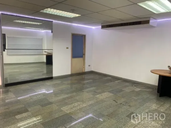 Office Space for rent in Khlong Toei, Bangkok - Spacious open-plan office with ducted AC, reflective tile floors and a glass wall divider.