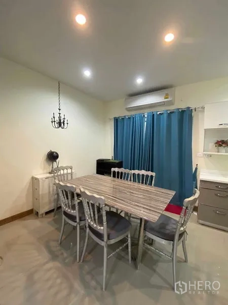 ทาวน์เฮาส์ ให้เช่าในSuan Luang, Bangkok - มุมรับประทานอาหารโต๊ะหกที่นั่ง ใต้ไฟดาวน์ไลท์และผ้าม่านสีน้ำเงิน