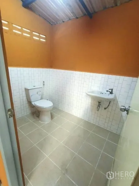 Factory for rent in Mueang Samut Sakhon, Samut Sakhon - Clean restroom with toilet, sink, tiled walls, and a high ceiling inside the factory.