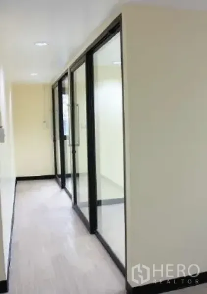 办公空间 出租在Bang Rak, Bangkok - 明亮走廊，玻璃隔断与浅色木地板的现代办公室。