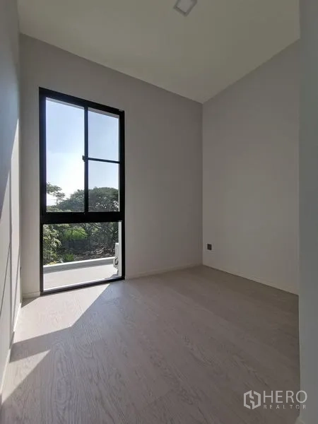 Detached House for sale in Saphan Sung, Bangkok - Compact bedroom with a tall window and leafy outdoor views.