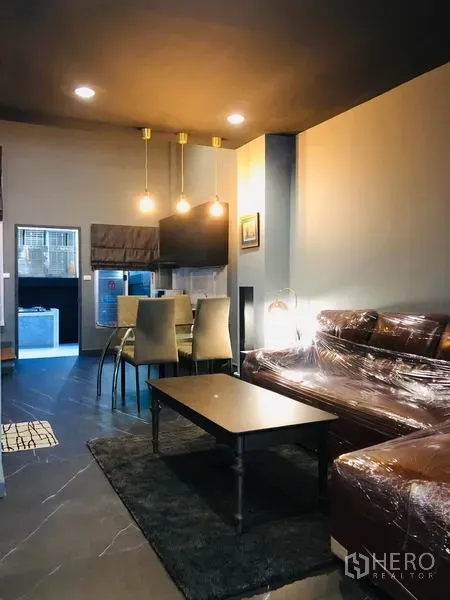 ทาวน์เฮาส์ ให้เช่าในBang Kapi, Bangkok - พื้นที่นั่งเล่นและทานอาหารแบบเปิด โล่ง โคมไฟแขวน โซฟาหนังและโต๊ะกลาง