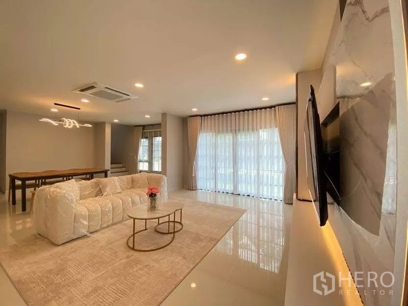 Detached House for rent in Bang Phli, Samut Prakan - Open-plan living area with sofa, marble TV wall and adjoining dining space.
