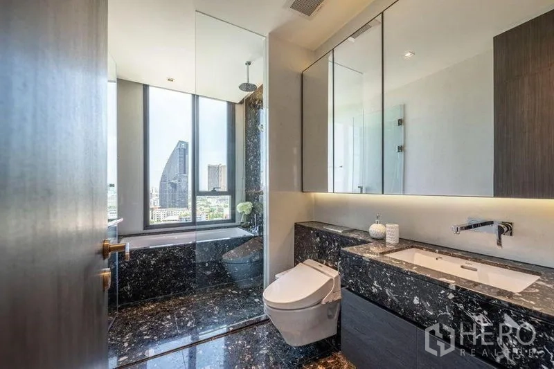 Condominium for rent in Khlong Toei, Bangkok - Luxurious bathroom with black marble vanity, soaking tub and picture windows to the skyline.