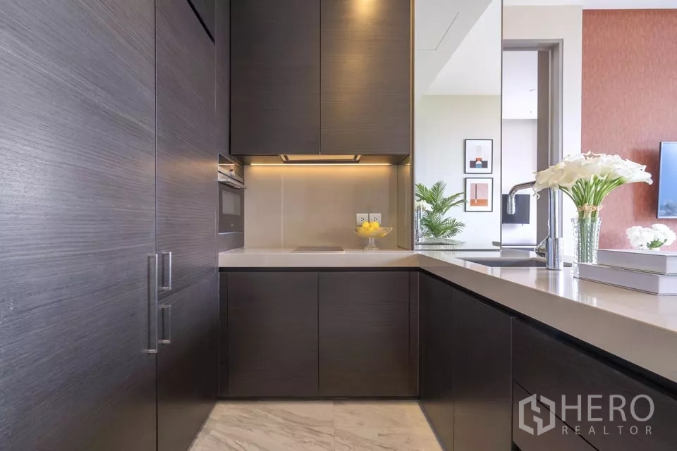 公寓 出租或出售在Bang Rak, Bangkok - 紧凑L形厨房，深色柜体与石材台面。