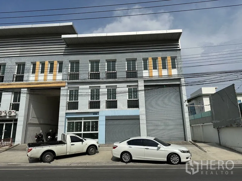 โรงงาน ให้เช่าในBang Sao Thong, Samut Prakan - อาคารโรงงาน-โกดัง 3 ชั้น หน้าอาคารมีประตูม้วนขนาดใหญ่และที่จอดรถริมถนน บางเสาธง.