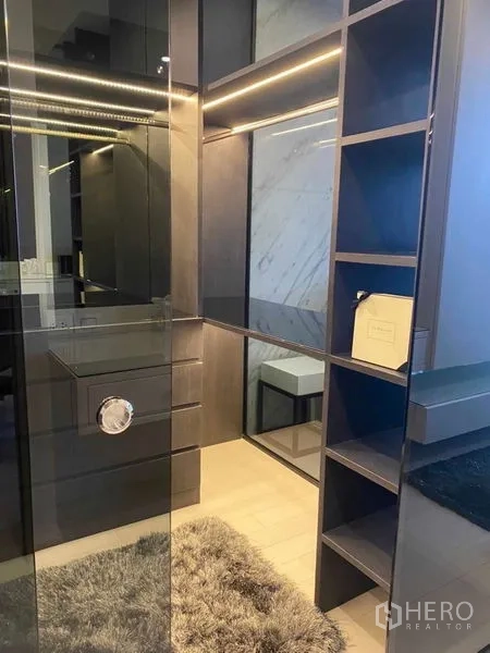 Condominium for sale in Pathum Wan, Bangkok - Walk-in closet with glass door, open shelving and soft LED lighting.