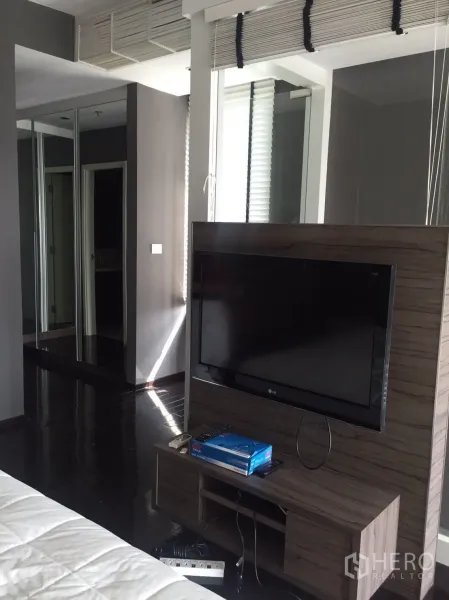 คอนโด ให้เช่าในKhlong Toei, Bangkok - มุมห้องนอนพร้อมชั้นวางทีวี ตู้เสื้อผ้าบานกระจก และพื้นไม้โทนเข้ม