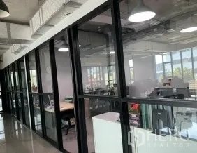 办公空间 出租在Phaya Thai, Bangkok - 落地玻璃墙后的开放式办公区，可见城市景观。