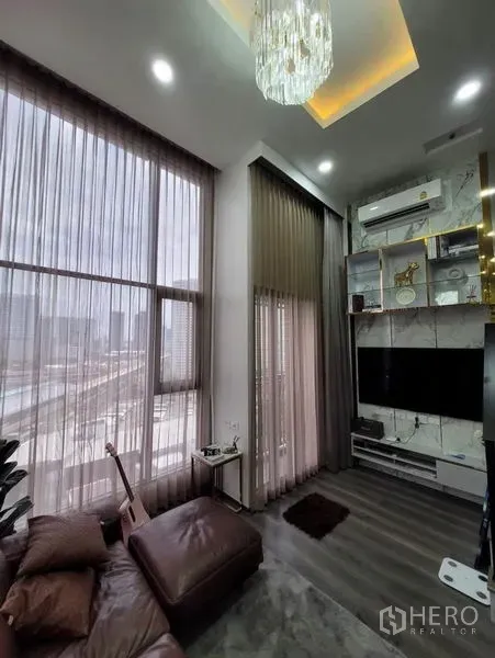 คอนโด ให้เช่าในChatuchak, Bangkok - มุมห้องนั่งเล่น โคมไฟคริสตัล ผนังทีวี ผ้าม่านโปร่ง และประตูกระจก