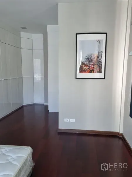 บ้าน ขายในChatuchak, Bangkok - ห้องนอนพื้นไม้สีเข้ม ตู้บิ้วท์อินสีขาว และภาพแขวนผนัง