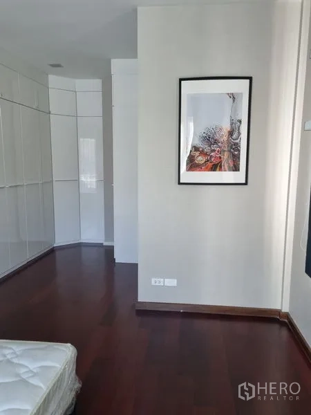 บ้าน ขายในChatuchak, Bangkok - ห้องนอนพื้นไม้สีเข้ม ตู้บิ้วท์อินสีขาว และภาพแขวนผนัง