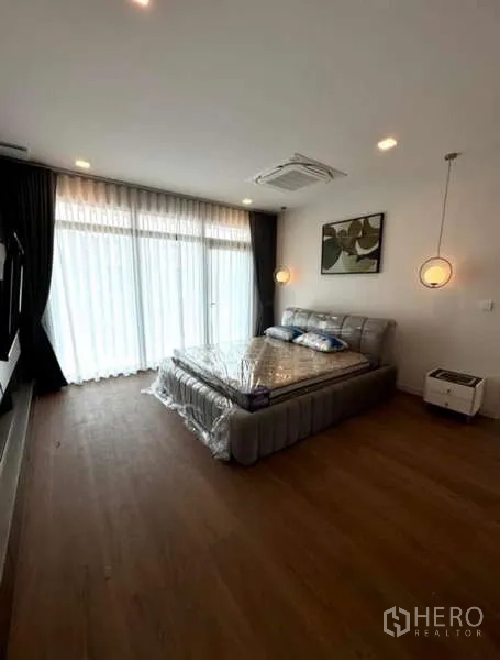 Detached House for rent in Samut Prakan - Master bedroom with pendant lights and full-height sheer curtains.
