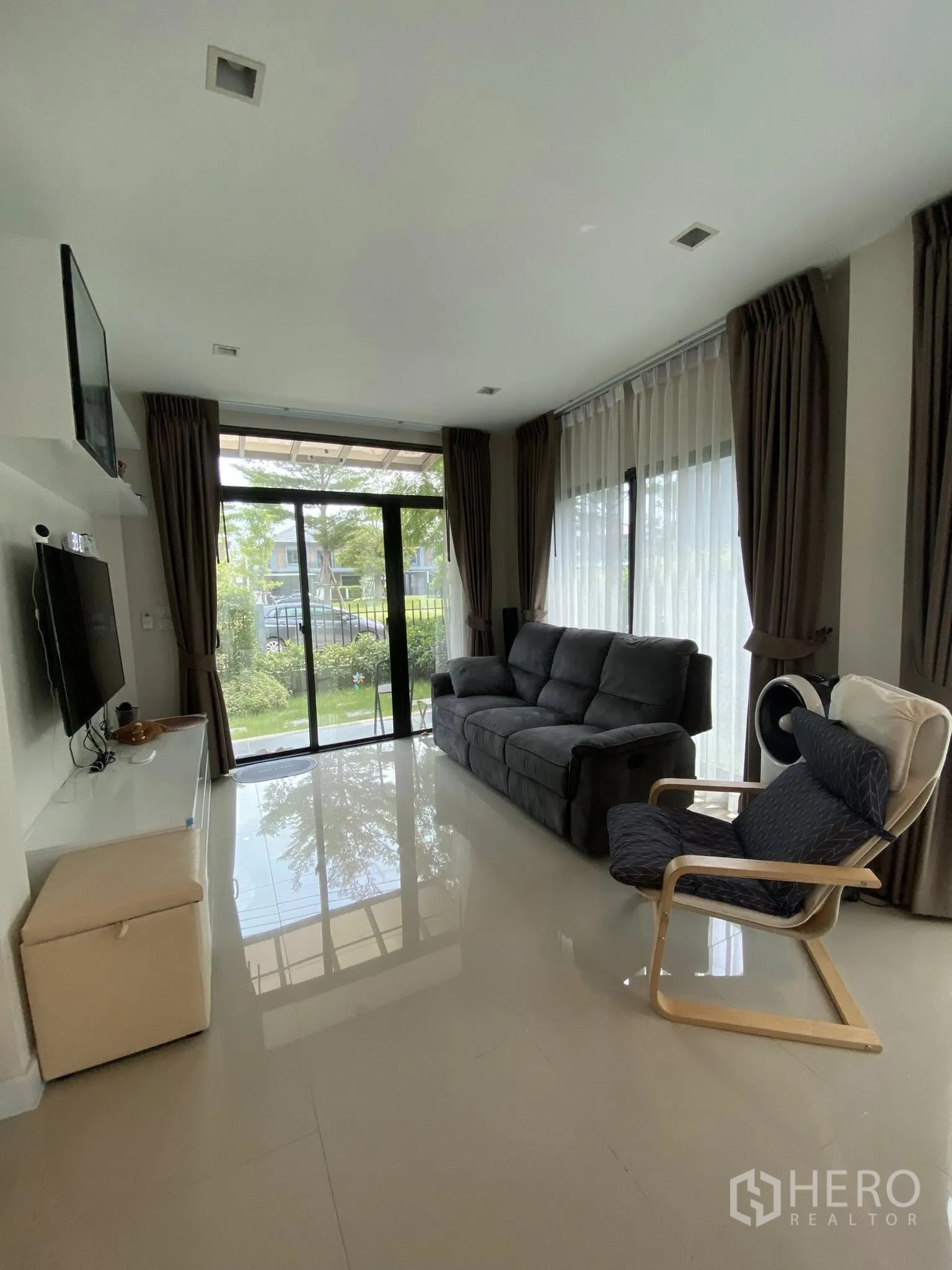 Detached House for sale in Saphan Sung, Bangkok - Living room with floor-to-ceiling glass doors opening to the front garden.