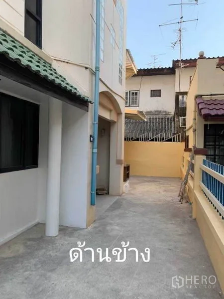 ทาวน์เฮาส์ ให้เช่าในPhra Khanong, Bangkok - ทางเดินด้านข้างตัวบ้าน ภายนอกสีครีม หลังคากระเบื้อง และทางเข้าประตูรั้ว