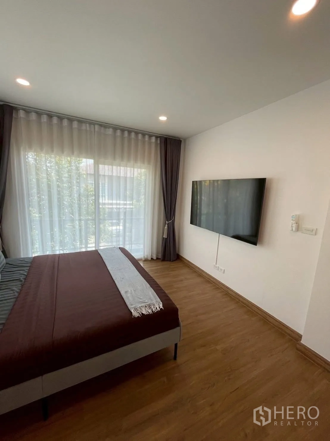 Detached House for rent in Prawet, Bangkok - Bedroom with bed, sheer curtains, wall-mounted TV and recessed lighting.
