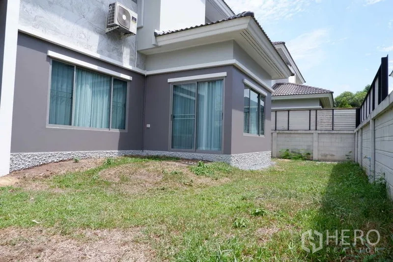 บ้าน ขายในLat Krabang, Bangkok - สนามหญ้าด้านข้างและประตูกระจกบ้านเดี่ยวสองชั้นในเขตลาดกระบัง กรุงเทพฯ