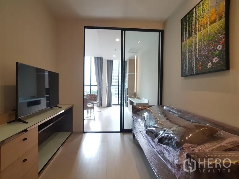 คอนโด ให้เช่าในPathum Wan, Bangkok - ห้องนั่งเล่นมีโซฟาและทีวี หน้าประตูกระจกบานเลื่อนไปยังห้องนอนสว่าง